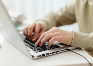 Person typing at a laptop while writing a Performance Improvement Plan
